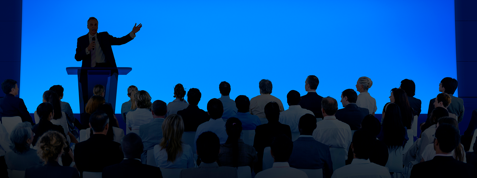 Silhouettes of conference speaker and audience banner image