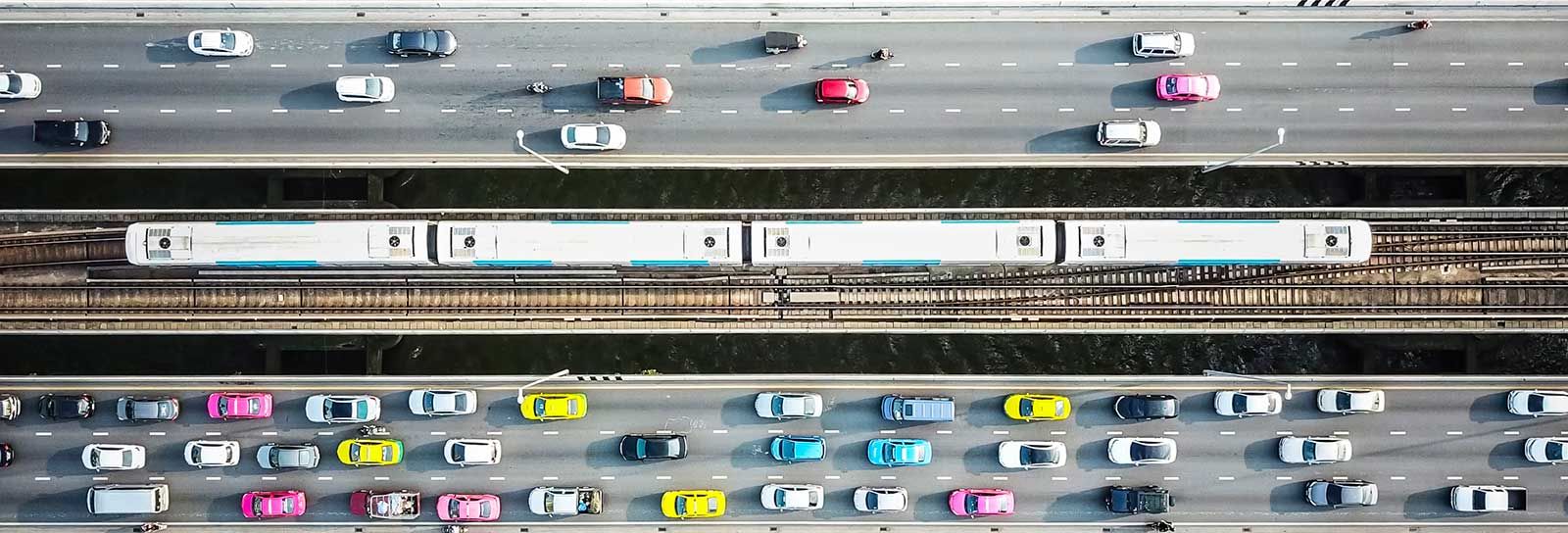 Aerial photo of cars and a train crossing a bridge banner image