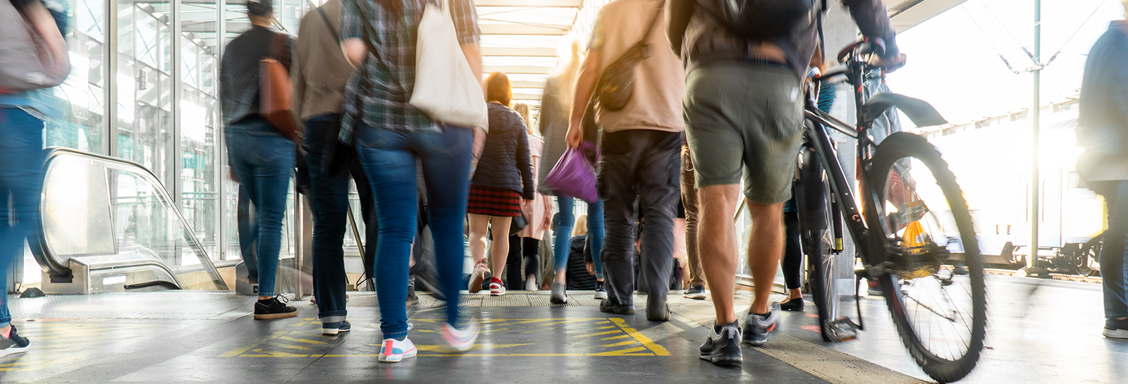 Pedestrians and cyclist on station platform banner image