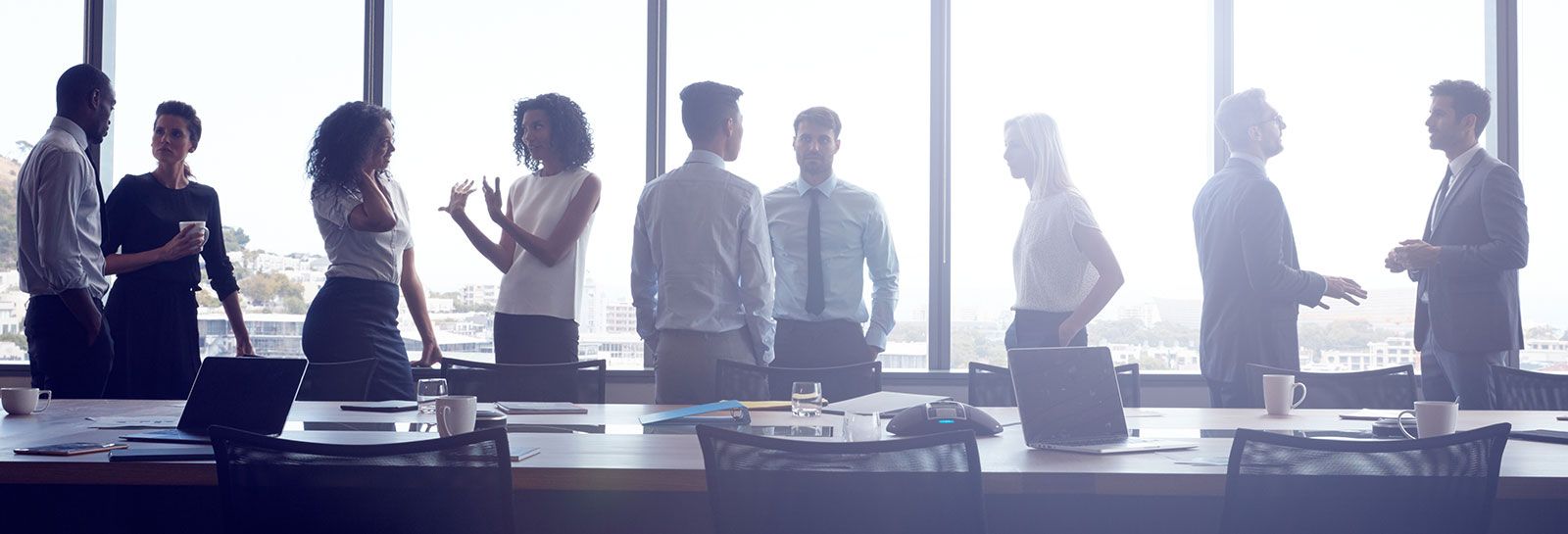 People standing and chatting in a meeting room banner image