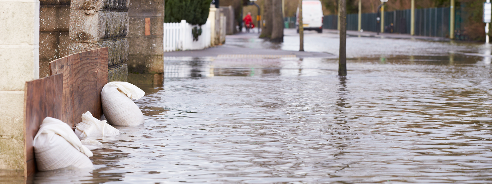 sandbags outside a house on a flooded road banner image